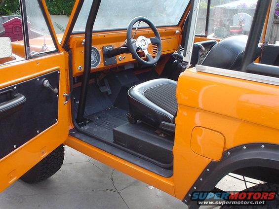 Orange 1977 Ford Bronco interior with black seats and roll cage