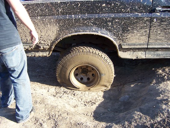Black SUV side view with flat tire in mud