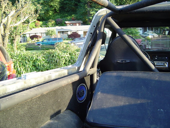 Interior view of a 1978 Ford Bronco with roll cage and racing seat. Rear seat visible
