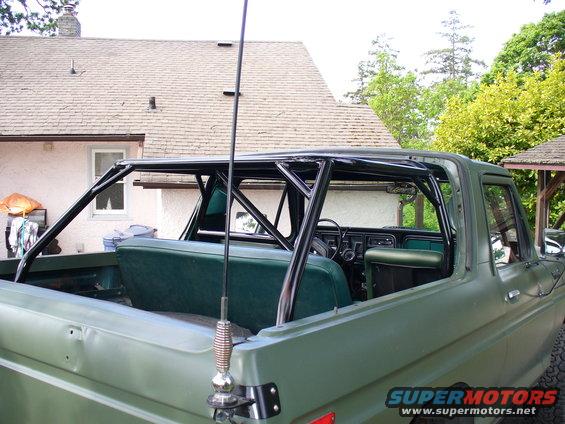 Green Ford Bronco interior with a black roll cage installed over the seats and dashboard