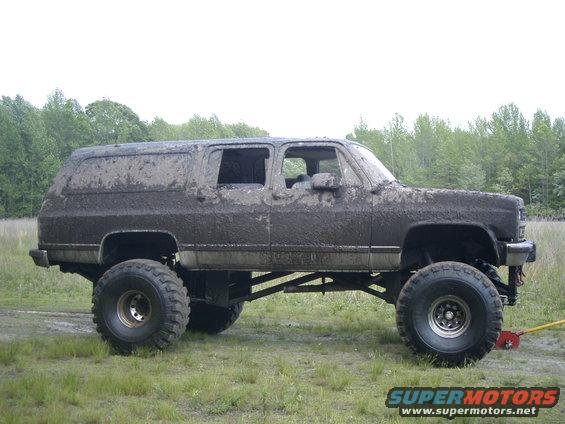 Side view of a mud-covered 1991 Chevrolet Suburban lifted with large tires