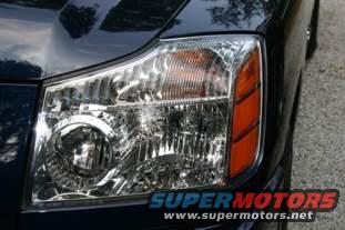 Dark blue truck headlight with orange turn signal. Supermotors.net logo visible