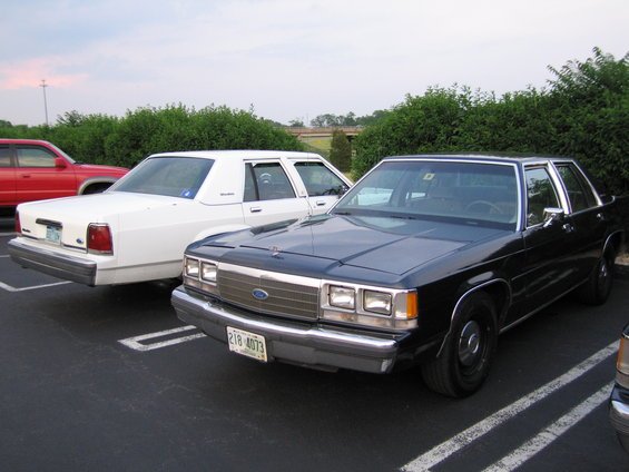 Dark blue Ford sedan parked next to a white sedan. License plate is 218 4073