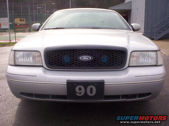 2002 Ford Crown Victoria front grille with black honeycomb pattern and Ford logo. License plate reads '90'