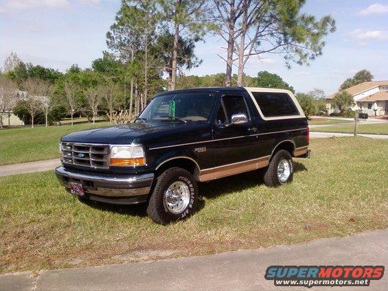 Black 1995 Ford Bronco parked on grass with a tan top
