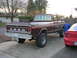 1978 Ford F-250 - This Ford pickup truck has a lifted suspension and large tires. A red car is parked to its right.