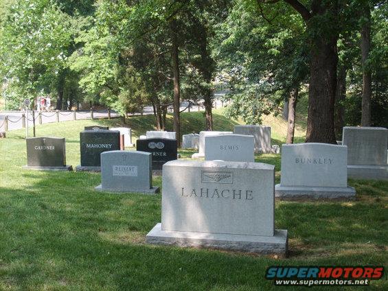 Gravestones with names like LAHACHE and BUNKLEY in a grassy cemetery with trees