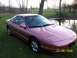 1996 Ford Probe - A pink 1996 Ford Probe is shown from a 3/4 front angle, parked on a grassy area next to a body of water.