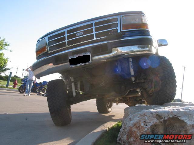Ford Bronco lifted on rocks, front view, blue body, chrome grille, large tires