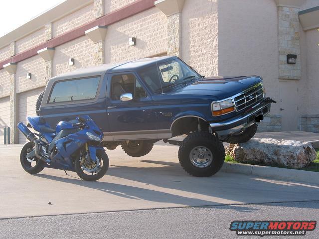 Blue 1996 Ford Bronco parked next to a blue motorcycle