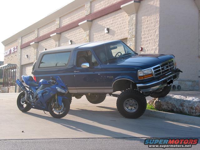 1996 Ford Bronco parked next to a blue sportbike motorcycle