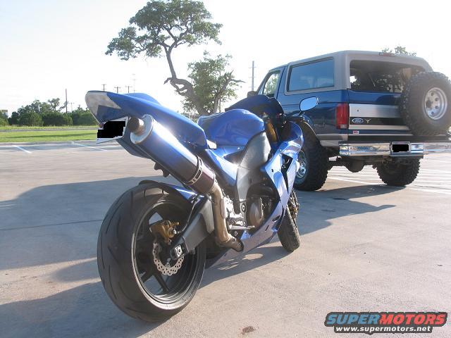 Rear view of a blue sportbike motorcycle parked next to a 1996 Ford Bronco