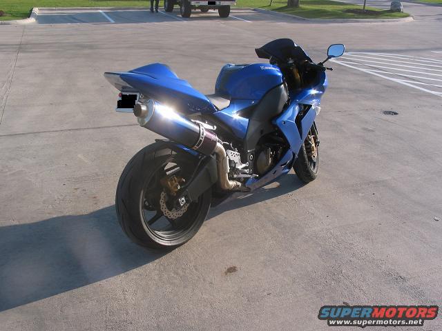 Blue Kawasaki motorcycle parked on concrete, rear three-quarter view