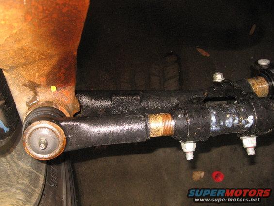 Close-up of a vehicle's tie rod end and drag link assembly, showing mechanical components and some markings