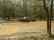 1991 Ford Bronco - A brown pickup truck navigates a muddy obstacle course in a wooded area.