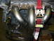 1993 Ford Taurus - Custom exhaust headers installed on an engine, secured with a red ratchet strap.