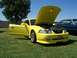 2002 Ford Mustang - A yellow Ford Mustang is displayed with its hood and driver's door open, revealing the engine compartment.