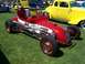 2002 Ford Mustang - A vintage race car is displayed on a grassy field with other classic vehicles in the background.