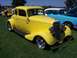 2002 Ford Mustang - A bright yellow hot rod coupe is displayed outdoors next to other vehicles.