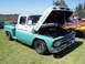 2002 Ford Mustang - A classic turquoise and white pickup truck is displayed with its hood open, parked on grass next to a car with flame graphics.