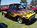 2002 Ford Mustang - Customized purple 1956 Ford F-100 pickup truck with vibrant flame graphics is displayed on a grassy field.