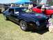 2002 Ford Mustang - Black 1977 Pontiac Trans Am with eagle decal on hood and "TRANS AM" text on fender.