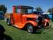 2002 Ford Mustang - An orange hot rod pickup truck with flame decals is parked on a grassy field with other vehicles in the background.