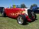 2002 Ford Mustang - A custom hot rod with flame graphics is displayed on a grassy field with other vehicles in the background.