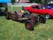 2002 Ford Mustang - A custom-built rat rod sits on grass next to a red muscle car under a blue tent.