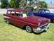 2002 Ford Mustang - A classic red Chevrolet Nomad station wagon is parked on a grassy lawn next to a blue pickup truck.