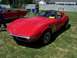 2002 Ford Mustang - A red convertible sports car is parked on a grassy field, with another classic red convertible visible behind it.