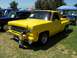 2002 Ford Mustang - A bright yellow pickup truck is parked on a grassy field, with a child examining its front bumper. Another vehicle is visible behind it.