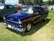 2002 Ford Mustang - A dark blue 1955 Chevrolet Bel Air sedan is parked on a grassy field at an outdoor event.
