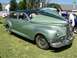 2002 Ford Mustang - A classic green sedan is displayed with its hood open, revealing the engine compartment to onlookers.