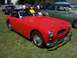 2002 Ford Mustang - A red convertible sports car is parked on a grassy field with other vehicles in the background.