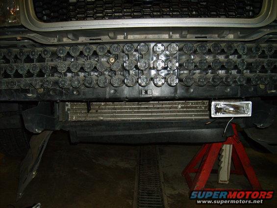 Front bumper area of a vehicle with a grille, radiator, and a fog light being installed