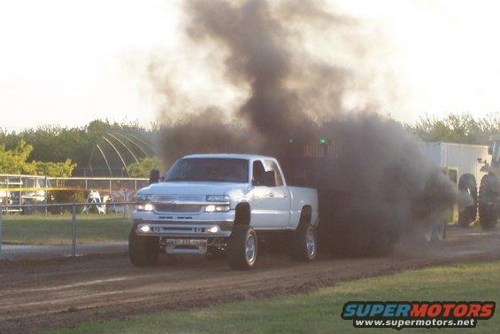 White pickup truck pulling a trailer, emitting heavy black smoke