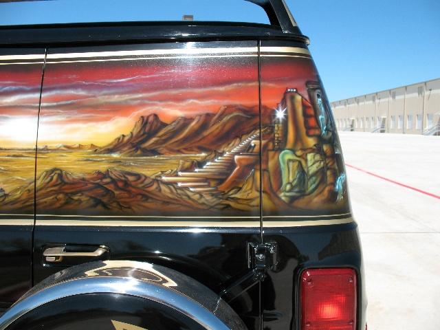 Side view of black van with desert landscape mural and stairs
