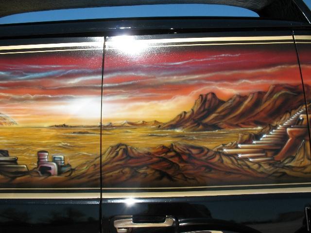 Side of a black van with a custom airbrushed desert landscape and staircase mural