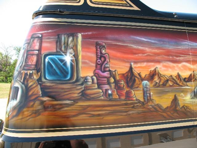 Van side with airbrushed desert landscape, tiki, and glowing screen