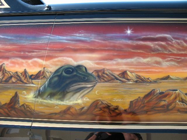 Side view of a vehicle with a custom airbrushed mural of a frog in a desert landscape