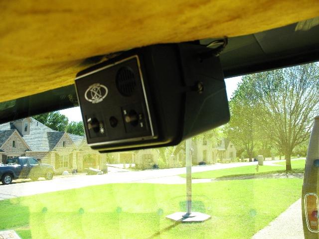 Black interior device with knobs and speaker mounted on yellow headliner, view through windshield