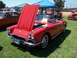 2002 Ford Mustang - A bright red 1962 Corvette convertible is displayed with its hood open, parked on a grassy field under a blue tent.