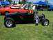 2002 Ford Mustang - A black hot rod with a powerful engine is parked on the grass at an outdoor car show.