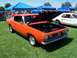 2002 Ford Mustang - An orange 1967 Plymouth Barracuda is displayed with its hood open at an outdoor car show.