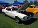 2002 Ford Mustang - A white 1967 Ford Mustang is displayed with its hood open, revealing the engine bay, alongside other vehicles at an outdoor event.