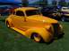 2002 Ford Mustang - A yellow hot rod coupe is parked on grass, with other vehicles and tents in the background.