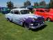 2002 Ford Mustang - A customized classic car with flame paint is displayed at an outdoor event with other vehicles.