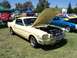 2002 Ford Mustang - A yellow 1965 Ford Mustang coupe is displayed with its hood open at an outdoor car show.