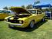 2002 Ford Mustang - A bright yellow 1969 Chevrolet Camaro Z/28 is displayed with its hood open, parked on a grassy field next to other vehicles.